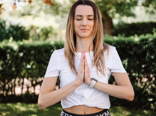 A serene moment of a woman practicing yoga with namaste pose outdoors, embracing mindfulness.