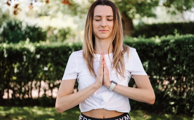 A serene moment of a woman practicing yoga with namaste pose outdoors, embracing mindfulness.